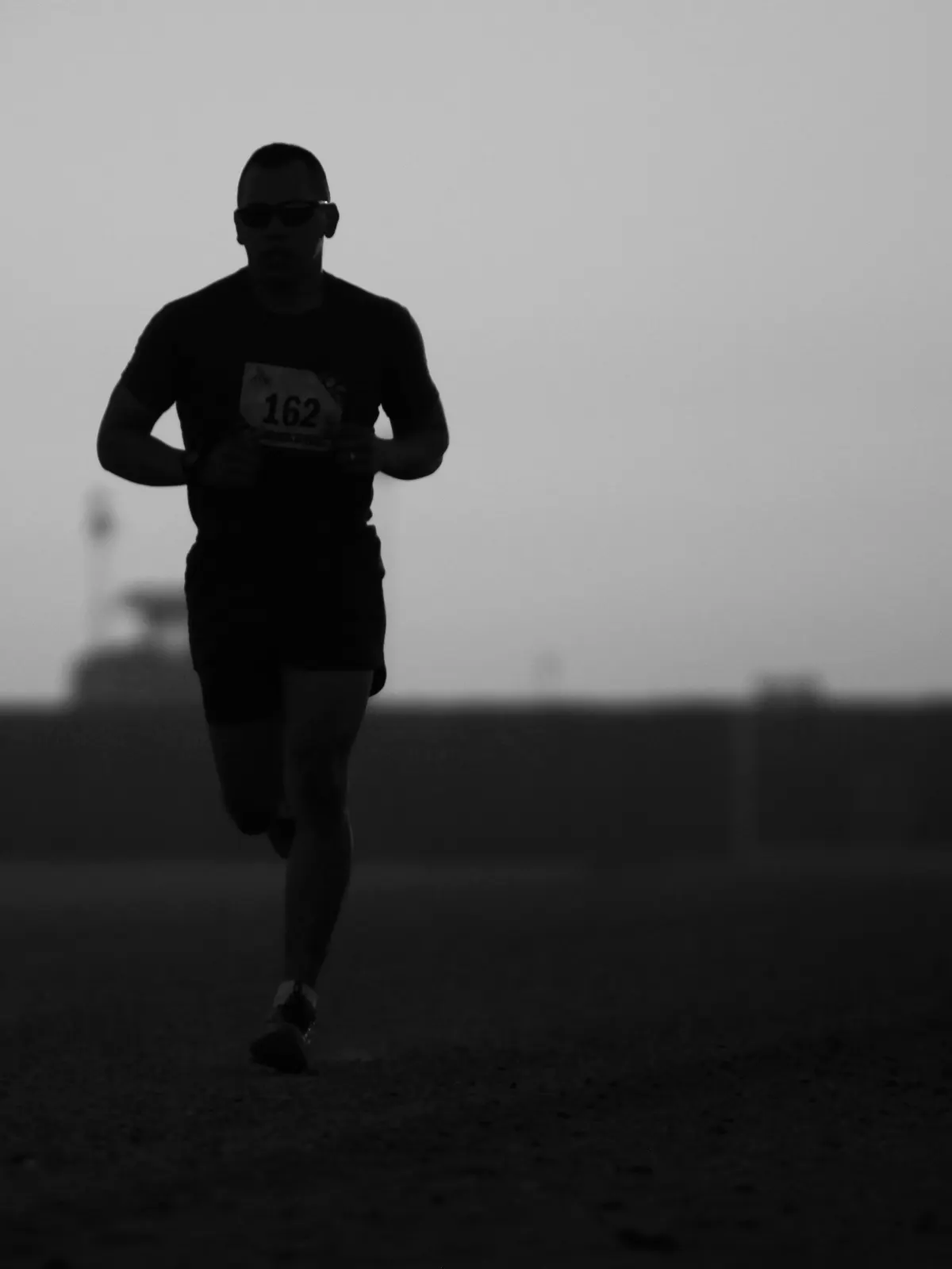 Silhouette of a runner approaching through early morning haze.